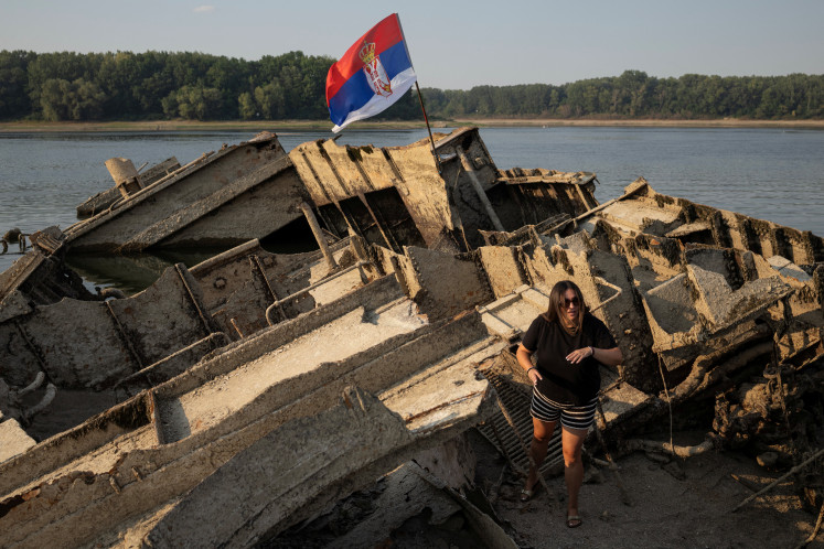 A woman stands on a sunken German warship from World War II, exposed due to low Danube river levels caused by drought and extreme heat near Prahovo, Serbia, on Aug. 13. 2026.