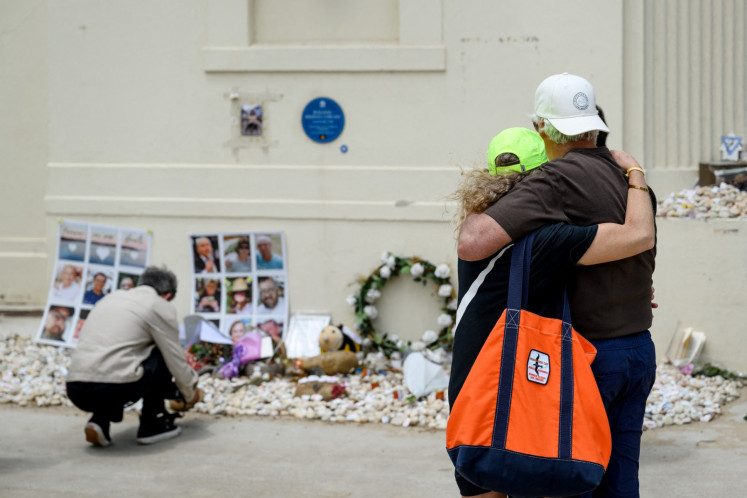 People comfort each other while looking at floral tributes in memory of the victims of the 2025 Bondi Beach shooting at the Bondi Pavilion in Sydney, Australia, on January 22, 2026, as part of the national day of mourning.