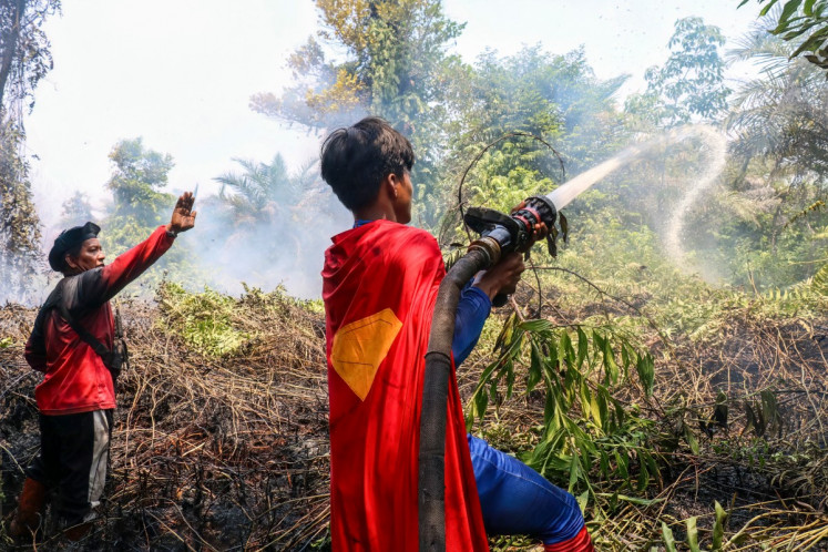 Student Rudiansyah (right) dressed in a Superman costume helps to extinguish a forest and land fire at Petuk Katimpun in Palangka Raya, Central Kalimantan, on August 17, 2026. 