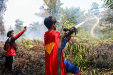 Student Rudiansyah (right) dressed in a Superman costume helps to extinguish a forest and land fire at Petuk Katimpun in Palangka Raya, Central Kalimantan, on August 17, 2026. 