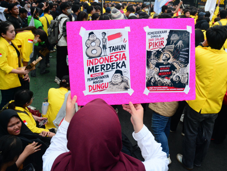 A woman holds a poster with caricatures criticizing government officials after 81 years of Indonesian independence on Aug. 18, 2026, during a protest on Jl. Thamrin in Central Jakarta against government policies, including state budget spending, the free nutritious meal program, the military&rsquo;s expanded role in civilian affairs and corruption eradication efforts.