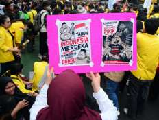 A woman holds a poster with caricatures criticizing government officials after 81 years of Indonesian independence on Aug. 18, 2026, during a protest on Jl. Thamrin in Central Jakarta against government policies, including state budget spending, the free nutritious meal program, the military&rsquo;s expanded role in civilian affairs and corruption eradication efforts.