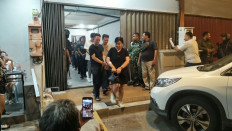 Detectives escort detainees during a raid at the Nine Stage Lounge and Bar in Nagoya Indah Shophouse Block B2 No. 9, in Batam, Riau Islands, on Aug. 15, 2026. Detectives from the National Police's Criminal Investigation Agency (Bareskrim) raided the gambling den in cooperation with the Riau Islands Police and Batam, Rempang and Galang (Barelang) Police, arresting 197 staff and gamblers as well as Rp 7.79 billion (US$435,715) in cash. 