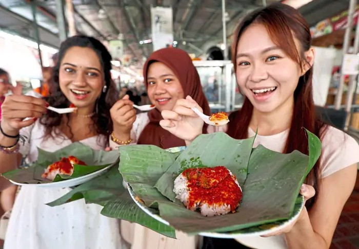 (From left) Joanne Chan Chiew Ean, Ain Nadzirah Othman and R. Reveka Nair, show their packets of nasi lemak in George Town, Malaysia, on June 28, 2025. 