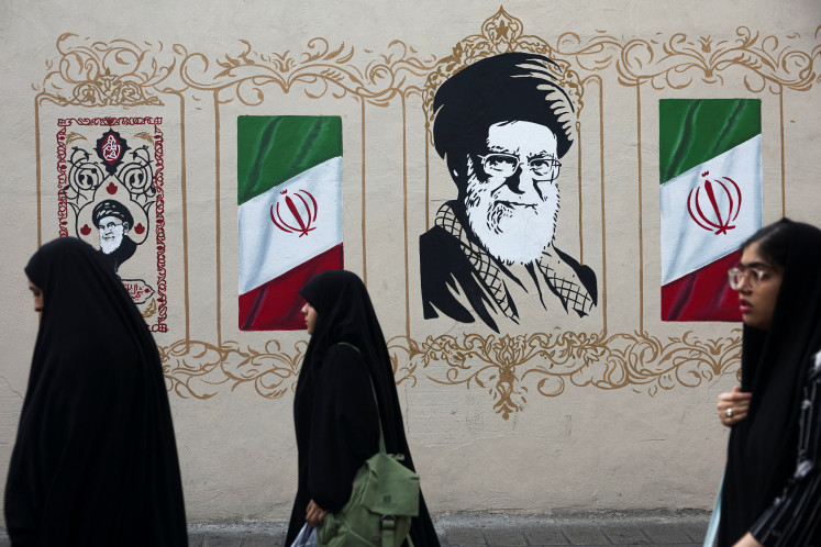 People walk by a mural depicting Iran's late Supreme Leader Ayatollah Ali Khamenei, on a street in Tehran, Iran, August 13, 2026.