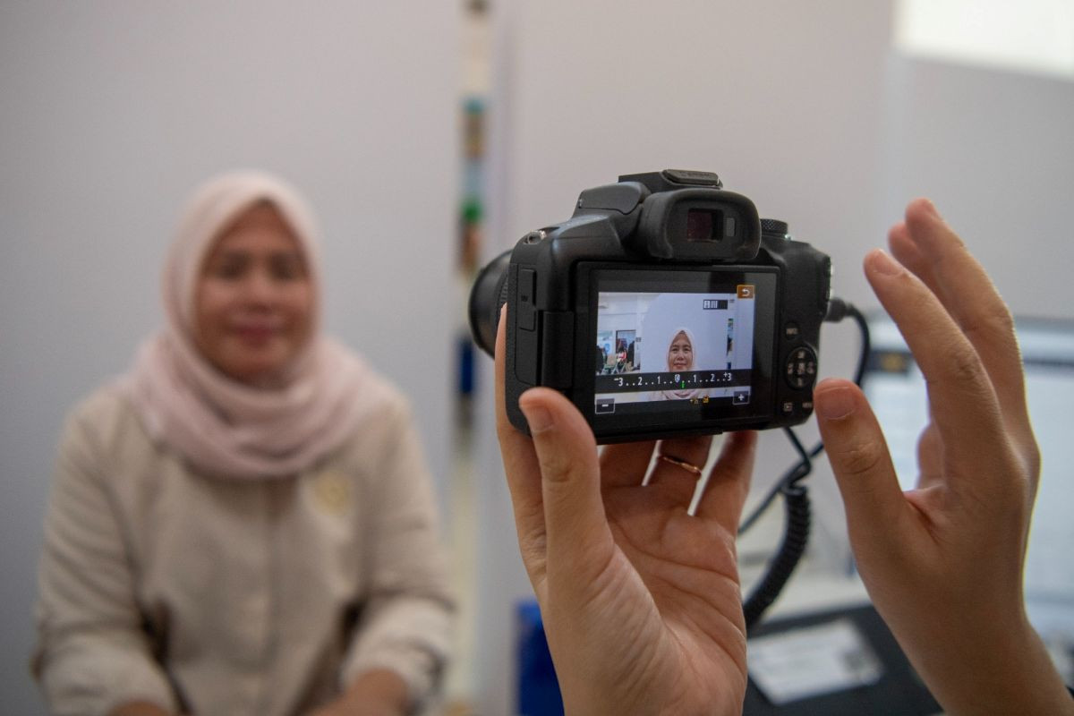 Headshot: An immigration officer takes a picture of a passport applicant at the Class I Immigration Office in Palembang, South Sumatra, on Aug. 3, 2026. 