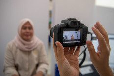 Headshot: An immigration officer takes a picture of a passport applicant at the Class I Immigration Office in Palembang, South Sumatra, on Aug. 3, 2026. 