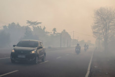 Motorists drive with headlights ong Aug. 20 along a haze-shrouded road in Palangkaraya, Central Kalimantan, as smoke originating from widespread forest and land fires has significantly reduced visibility and degraded air quality across the province. Indonesia's government says over 100,000 hectares burned in the first half of the year. 