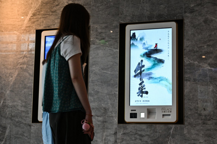 People walk past ticket machines advertising films including &ldquo;Niu Lai&ldquo; (right), which translates to &ldquo;Here Comes the Cow&ldquo;, at a cinema in Shanghai on Aug. 21, 2026. &ldquo;Niu Lai&ldquo;, a low-budget Chinese animated film that was widely mocked for its crude visuals became a viral hit, with people packing cinemas to see just how bad it is.