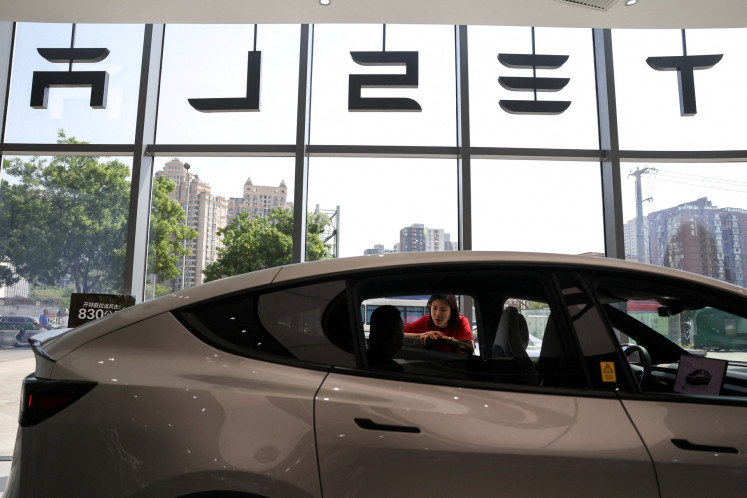 A staff member attends to a customer next to a Model Y L electric car inside a Tesla store at a shopping mall in Beijing, China, on May 12, 2026.