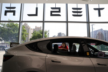 A staff member attends to a customer next to a Model Y L electric car inside a Tesla store at a shopping mall in Beijing, China, on May 12, 2026.