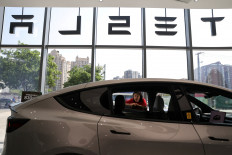 A staff member attends to a customer next to a Model Y L electric car inside a Tesla store at a shopping mall in Beijing, China, on May 12, 2026.