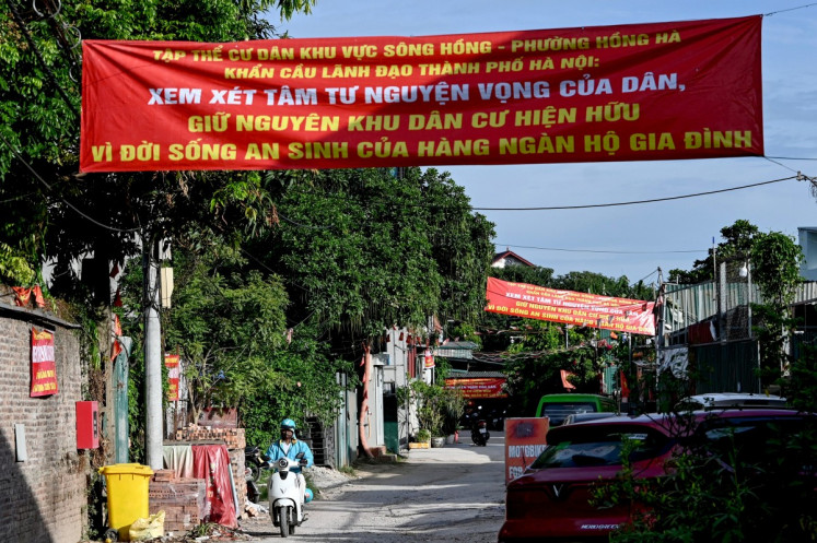 A protest banner, which reads &ldquo;The residents of the Red River area in Hong Ha Ward earnestly appeal to city leaders to consider the people's inner thoughts and aspirations, maintaining the existing residential area for the sake of the well-being of thousands of households&rdquo;, hangs over a street at a neighborhood in Hanoi, on June 19, 2026.