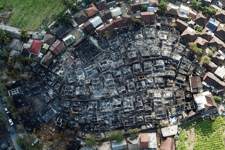Structures untouched by fire surround what was once the site of Sade on Aug. 23, 2026, a day after a blaze tore through the indigenous Sasak hamlet in Lombok, West Nusa Tenggara.