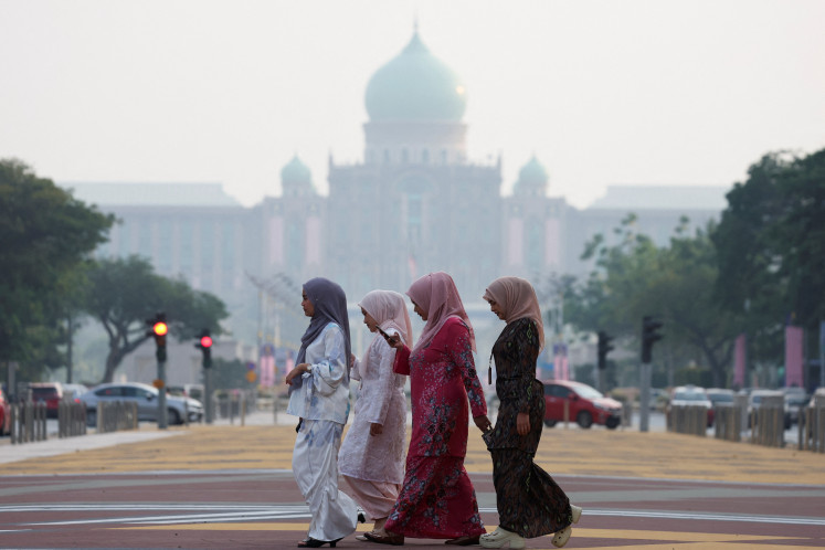 A group of women crosses in front of Perdana Putra, the office of the prime minister in Malaysia&rsquo;s administrative capital Putrajaya, shrouded in haze from regional wildfires on Aug. 13, 2026.
