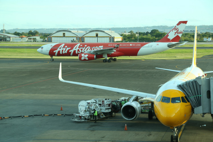 An airplane operated by Singapore's Scoot airline (right) is being refueled while another aircraft by Indonesian Air Asia is passing in the taxiway at the I Gusti Ngurah Rai International Airport in Denpasar, Bali on Feb. 19, 2018.