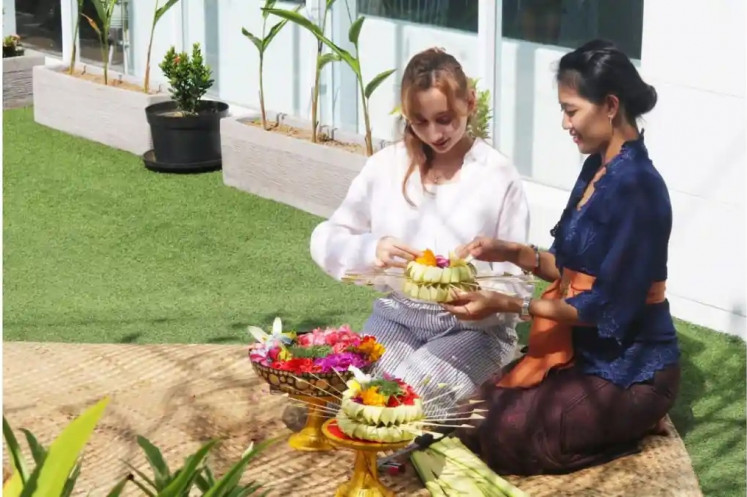 An instructor (right) teaches a tourist how to make a canang sari offering during a workshop at a resort in Jimbaran, Bali.