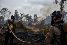 Police in firefighting gear extinguish a peatland fire at Tambang in Kampar, Riau, on Aug. 25, 2026. 
