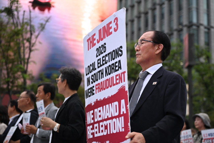A man holds a banner claiming local elections held in June were fraudulent, during a protest demanding new elections on July 23 in Seoul.