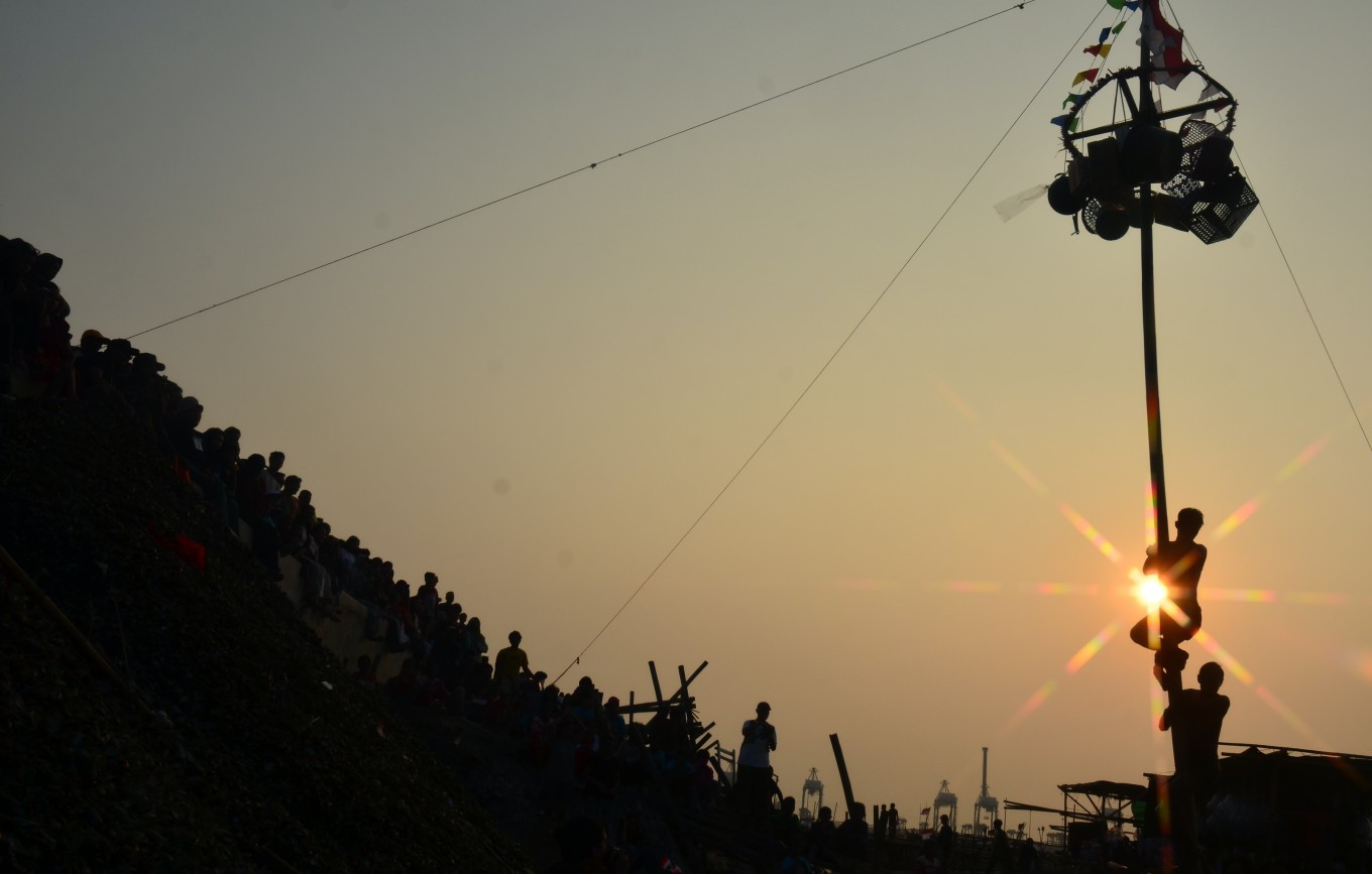 A silhouette of participants attempting to reach the top of a greased pole on Aug. 17, 2026, during an annual traditional pole-climbing competition held to mark Indonesia&rsquo;s Independence Day in the Cilincing area of North Jakarta.