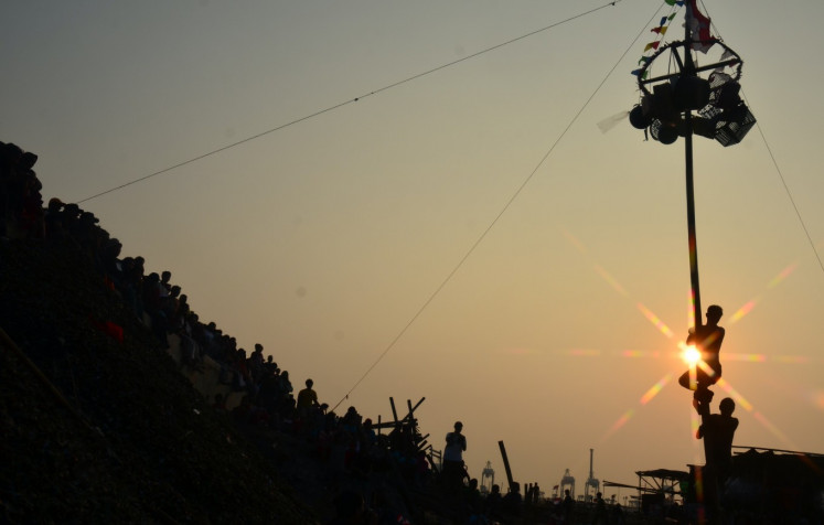 A silhouette of participants attempting to reach the top of a greased pole on Aug. 17, 2026, during an annual traditional pole-climbing competition held to mark Indonesia&rsquo;s Independence Day in the Cilincing area of North Jakarta.