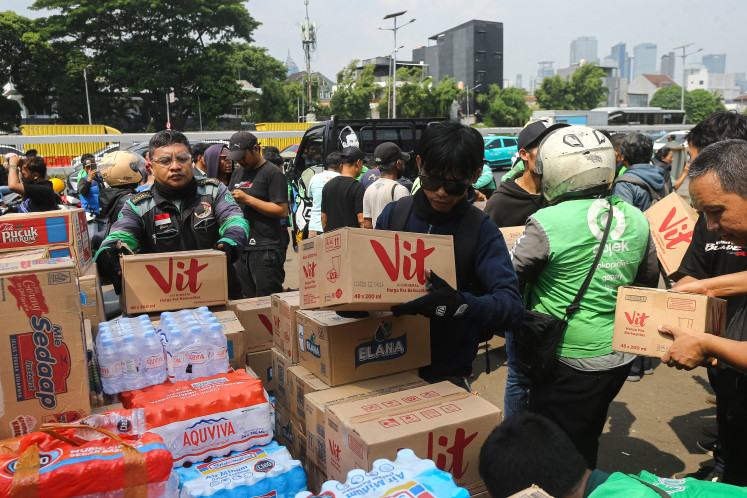 Residents and online motorcycle taxi drivers arrange boxes of bottled water donated by members of the public for participants of the United Pati People&rsquo;s Alliance (AMPB) rally outside the Senayan Legislative Complex in Central Jakarta on Aug. 26, 2026. 