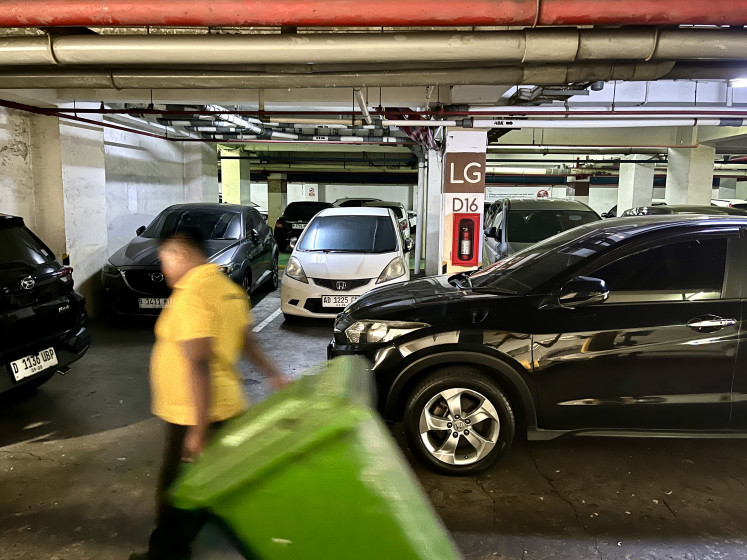 A sanitation worker walks through a parking lot at an apartment complex on Jl. Jend. Basuki Rachmat in East Jakarta, Thursday, Aug. 27, 2026.