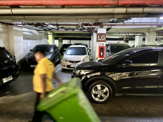 A sanitation worker walks through a parking lot at an apartment complex on Jl. Jend. Basuki Rachmat in East Jakarta, Thursday, Aug. 27, 2026.