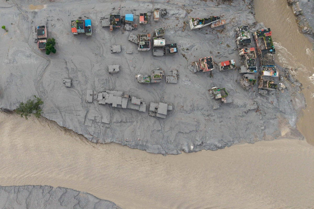 An aerial view shows houses lying deluged in sludge after flash floods at Devighat, Bidur Municipality, along the confluence of the Trishuli and Tadi rivers in Nepal's Nuwakot district on August 27, 2026. Nepal's disaster agency said that 823 people remained out of contact on August 27, more than 24 hours after a deadly flood tore through the border region with Tibet. 