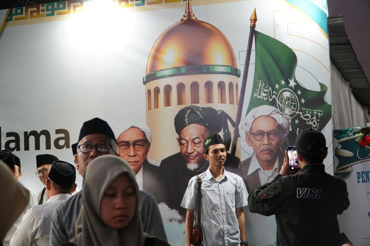 Opening stage: A participant takes a photo in front of a banner for the 35th Nahdlatul Ulama National Congress (Muktamar NU) on Aug. 27, 2026, after the five-day conference opened at Untung Suropati Field in the sprawling complex of Pondok Pesantren Bahrul Ulum Tambakberas, an Islamic boarding school in Jombang regency, East Java