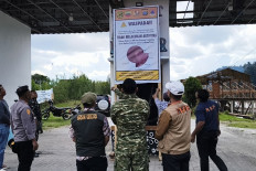 Officials from various agencies look on as two men install a poster warning residents and tourists not to approach Mount Sinabung on Aug. 29 in Karo regency, North Sumatra. The Mount Sinabung Monitoring Post has increased the volcano's status to Level II Waspada (advisory) following increased volcanic activities.
