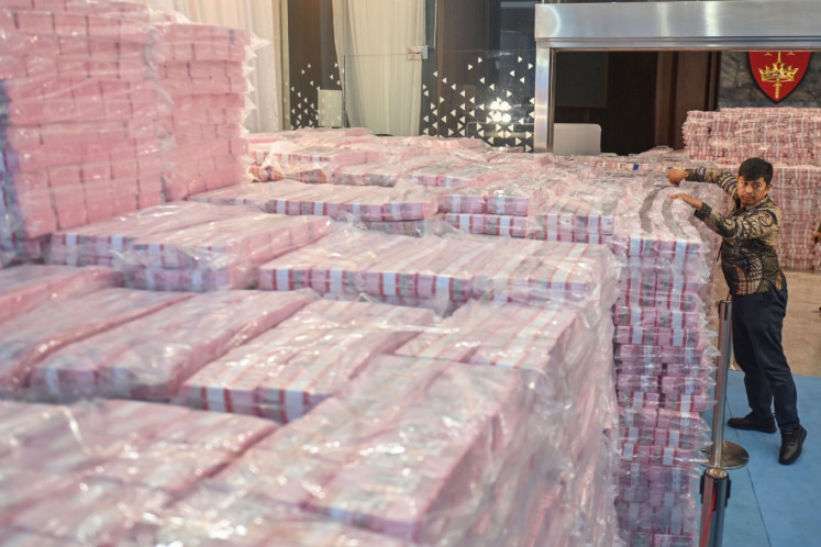 Officials arrange stacks of money collected from forestry administrative fines and recovered state assets from corruption cases on Dec. 24, 2025, at the Attorney General&rsquo;s Office complex in Jakarta.