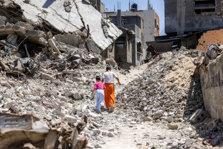 Two girls walk past the rubble of collapsed buildings on Aug. 25 in Khan Yunis in the southern Gaza Strip. A ceasefire in October 2025 has reduced but not halted the violence in Gaza. Israeli operations have killed 1,288 people since the ceasefire came into effect, according to Gaza's health ministry, which also operates under Hamas authority and whose figures are considered reliable by the United Nations.