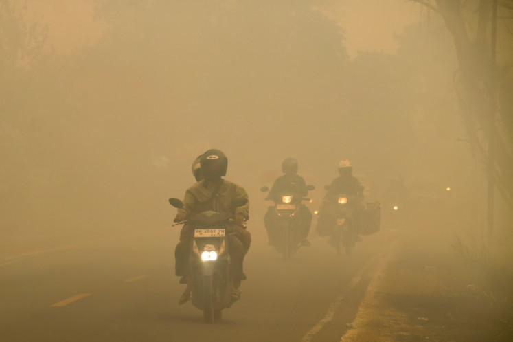 Motorcyclists ride on a haze-shrouded road caused by forest and land fires in Palangkaraya city, Central Kalimantan, on August 28, 2026.