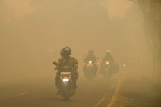 Motorcyclists ride on a haze-shrouded road caused by forest and land fires in Palangkaraya city, Central Kalimantan, on August 28, 2026.