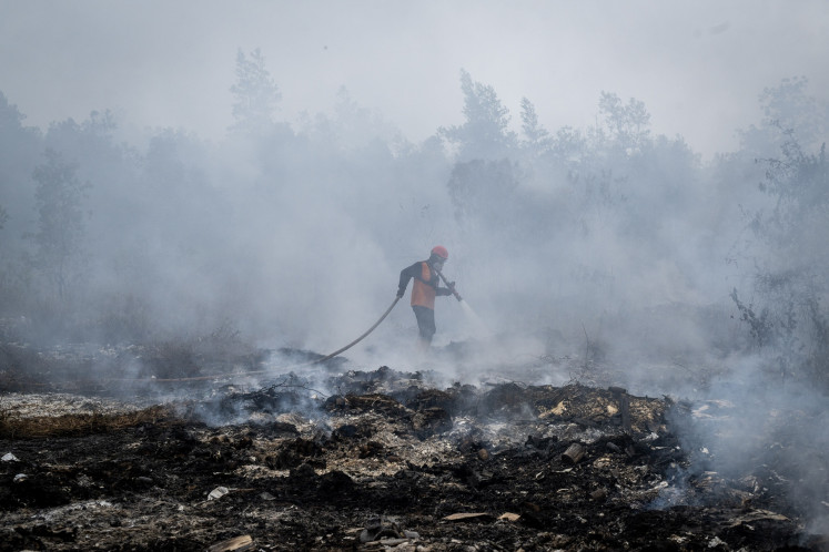 A firefighter from the Banjar Disaster Mitigation Agency (BPBD) douses a peatland fire on Sept. 2, 2026, in Banjar regency, South Kalimantan.