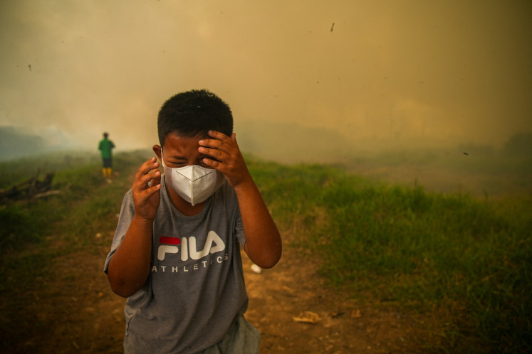 A boy reacts as smoke rises from&nbsp;wildfires in a residential area in Ogan Ilir, South Sumatra, on Sept. 2, 2026. 