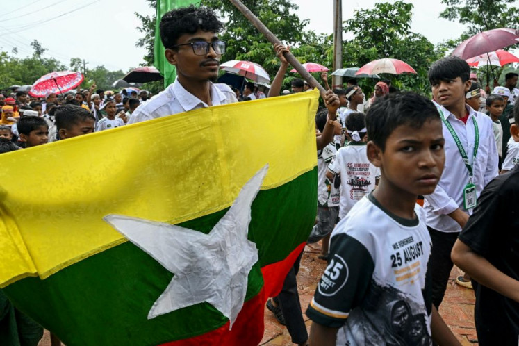 Stateless outcasts: A Rohingya man carries Myanmar's national flag on Aug. 25, 2026 during a Genocide Remembrance Day rally at a refugee camp in Cox's Bazar, Bangladesh, to mark the ninth anniversary of their mass exodus following a military crackdown.