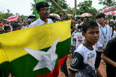 Stateless outcasts: A Rohingya man carries Myanmar's national flag on Aug. 25, 2026 during a Genocide Remembrance Day rally at a refugee camp in Cox's Bazar, Bangladesh, to mark the ninth anniversary of their mass exodus following a military crackdown.