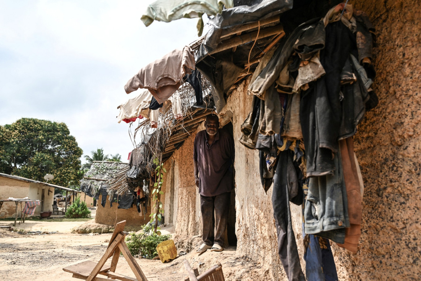 Boniface Djabia, the chief of Betykro, a camp of cocoa producers living in precarious conditions 20 kilometers from Guiglo,  Ivory Coast, poses for a portrait in front of one of his mud houses covered with straw on Jan. 16, 2026.