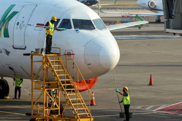 Workers wipe down a Citilink Airbus A320 aircraft parked on the apron of the Soekarno-Hatta airport in Tangerang, Banten, on September 7, 2026, after flight operations were suspended following the eruption of Mount Anak Krakatau. Indonesia's main airport postponed reopening on September 7 after halting operations following a volcanic eruption that left hundreds of thousands of passengers stranded. 