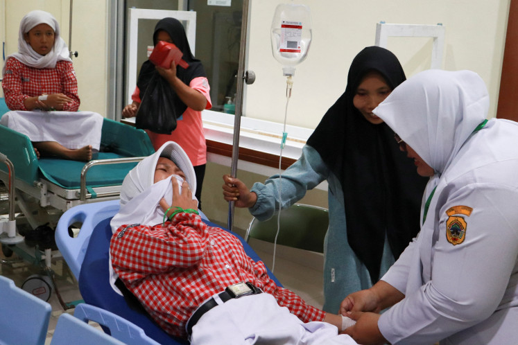 A student reacts while receiving treatment for food poisoning on Sept. 9 at the regional general hospital after eating a government-sponsored free meal in Pati, Central Java.