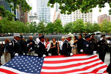 Law enforcement officers carry a United States flag next to the reflecting pools at the 9/11 Memorial during a ceremony marking the 25th anniversary of the Sept. 11, 2001 attacks on the World Trade Center, in New York City, the US, on Sept. 11, 2026.