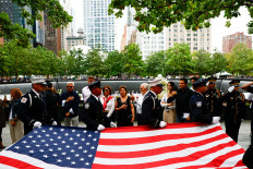 Law enforcement officers carry a United States flag next to the reflecting pools at the 9/11 Memorial during a ceremony marking the 25th anniversary of the Sept. 11, 2001 attacks on the World Trade Center, in New York City, the US, on Sept. 11, 2026.