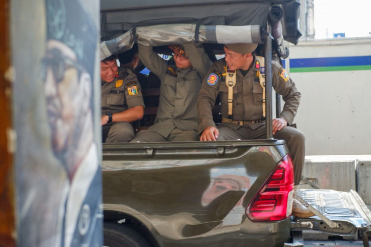 Jakarta Public Order Agency (Satpol PP) personnel sit in the agency's patrol car on Jan. 10, 2024,  in Jakarta.