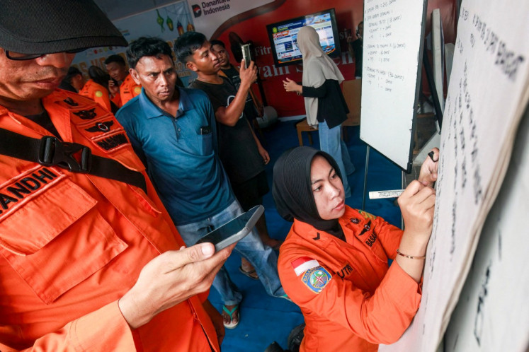 Relatives of affected passengers look on as a National Search and Rescue Agency (Basarnas) officer writes updates on a whiteboard amid ongoing rescue operations on the stricken Virgo Transport 8 ferry, at Trisakti Bandarmasih Port in Banjarmasin, South Kalimantan, on September 13, 2026. 