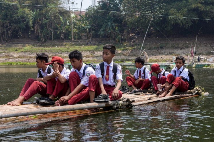 Elementary school children use a bamboo raft to cross the Citarum River on their way home in Saguling, Bandung, West Java, on Sept. 1, 2026. 