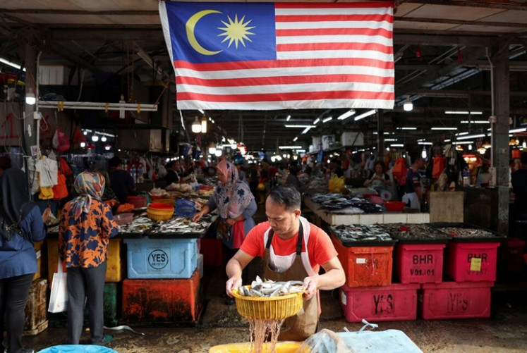 A fishmonger holds a basket of fish on Oct. 18, 2024, at a wet market in Kuala Lumpur. 