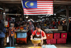 A fishmonger holds a basket of fish on Oct. 18, 2024, at a wet market in Kuala Lumpur. 