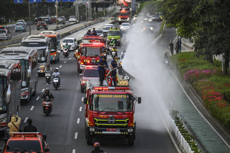 Firefighters spray water along Jl. Sudirman in Central Jakarta on Sept. 9, 2026 to clear volcanic ash spewed from Mount Anak Krakatau's eruption.